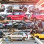 Red, blue, silver, and yellow cars on shelves in a salvage yard