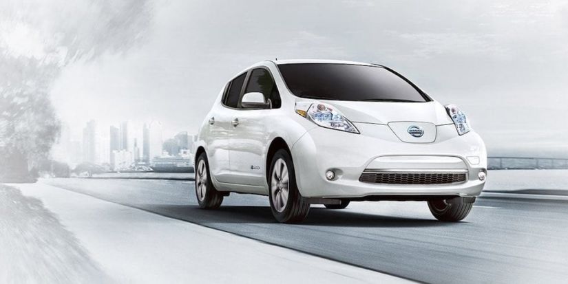 An overexposed image of a white 2017 Nissan Leaf driving away from a city