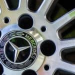Up close of the center of a car wheel with the words "Mercedes Benz" written around the silver Mercedes logo