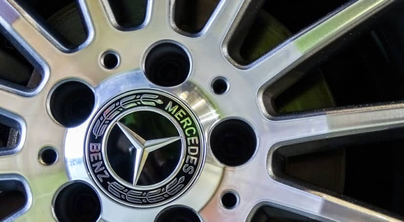 Up close of the center of a car wheel with the words "Mercedes Benz" written around the silver Mercedes logo