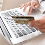 Close-up woman's hands holding a credit card and using computer keyboard for online shopping