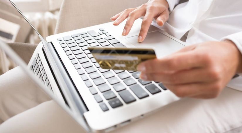 Close-up woman's hands holding a credit card and using computer keyboard for online shopping