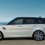 A white 2018 Range Rover Sport charging charging in a wide open parking lot with the ocean in the distance