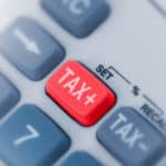 Close up of grey calculator buttons and one red button that says "TAX+"