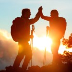 Hiking people reaching summit top high five