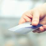 Hand holding out a blue and silver credit card