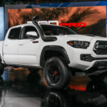 A white Toyota Tacoma with a snorkel at an Current Auto News car show