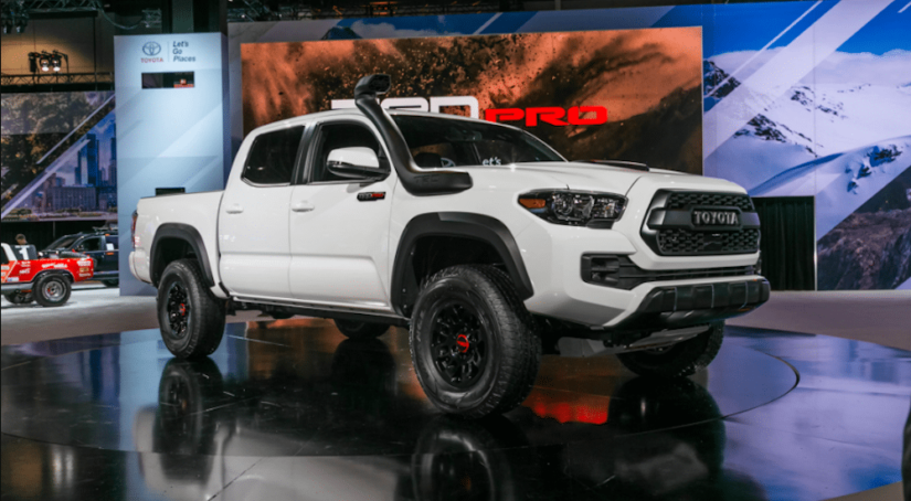 A white Toyota Tacoma with a snorkel at an Current Auto News car show
