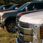 A closeup of the front hoods of pickup trucks in a line from Dealerships in Fort Worth on grass