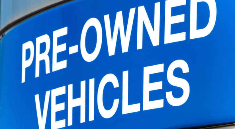 White lettering on a blue background that says "PRE-OWNED VEHICLES"