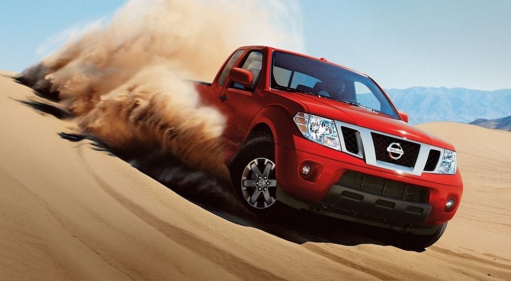 Red 2018 Nissan Frontier driving on dunes