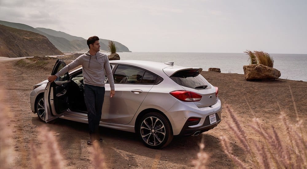Man stepping out of silver 2019 Chevy Cruze hatchback at beach