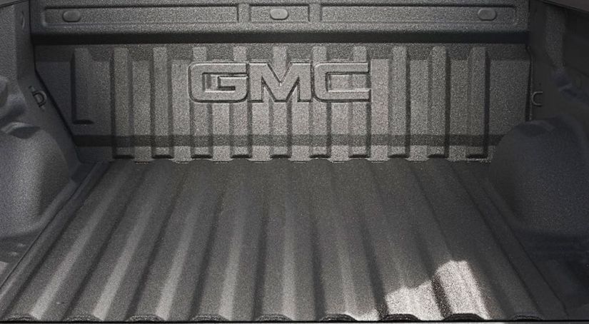 GMC logo on tailgate of pickup truck bed with black spray on bedliner