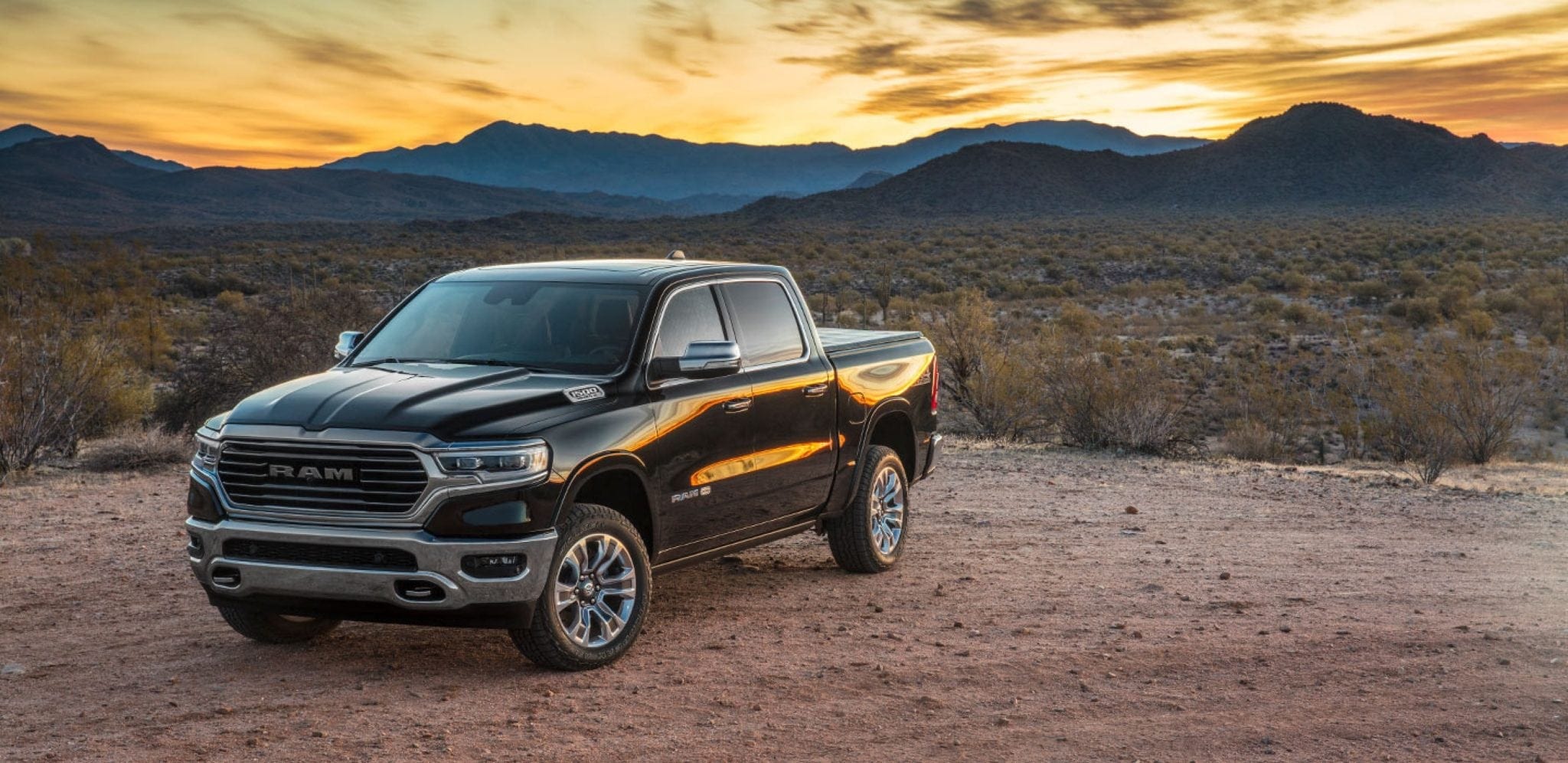 Black 2019 Ram 1500 Laramie with plains and mountains against a vibrant yellow sunset