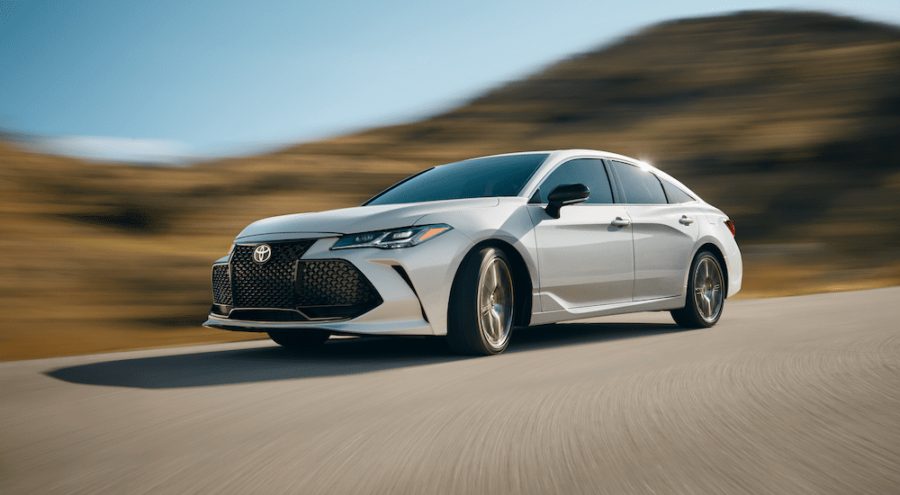 White 2019 Toyota Avalon driving around corner, out of focus background