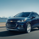 Blue 2019 Chevy Trax on highway with city in back