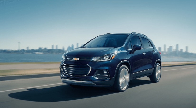 Blue 2019 Chevy Trax on highway with city in back