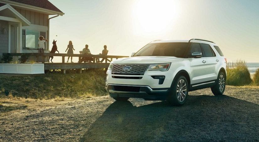 White 2019 Ford Explorer at beach with family on beach house deck in back