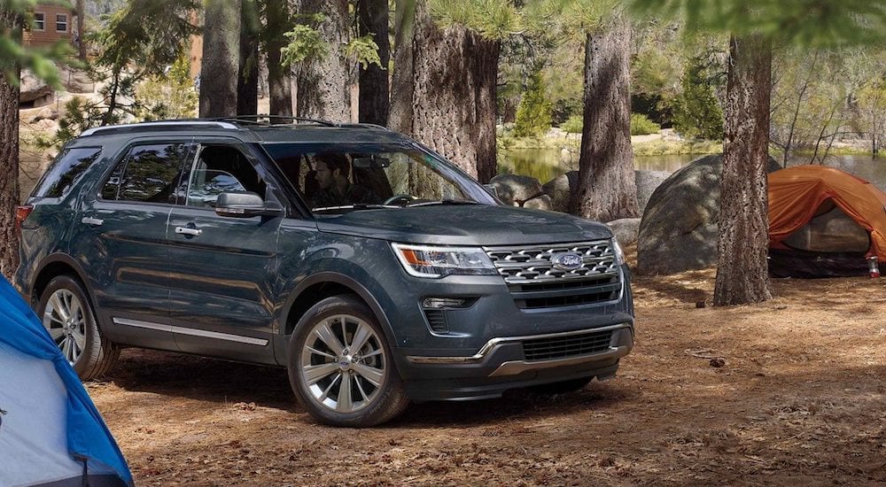 Blue 2019 Ford Explorer in woods with tents