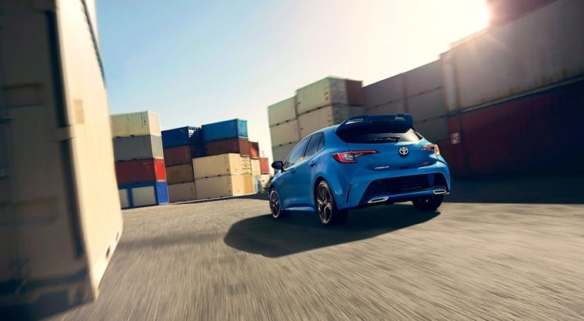 Blue 2019 Toyota Corolla driving between shipping containers
