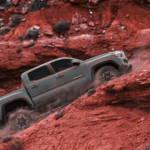 Gray 2019 Toyota Tacoma covered in dust climbing red mountains
