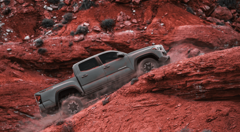 Gray 2019 Toyota Tacoma covered in dust climbing red mountains