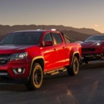Red Chevy Colorado towing a red Chevy Corvette in desert