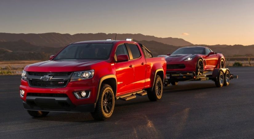 Red Chevy Colorado towing a red Chevy Corvette in desert
