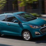 Teal 2019 Chevy Spark driving on city street