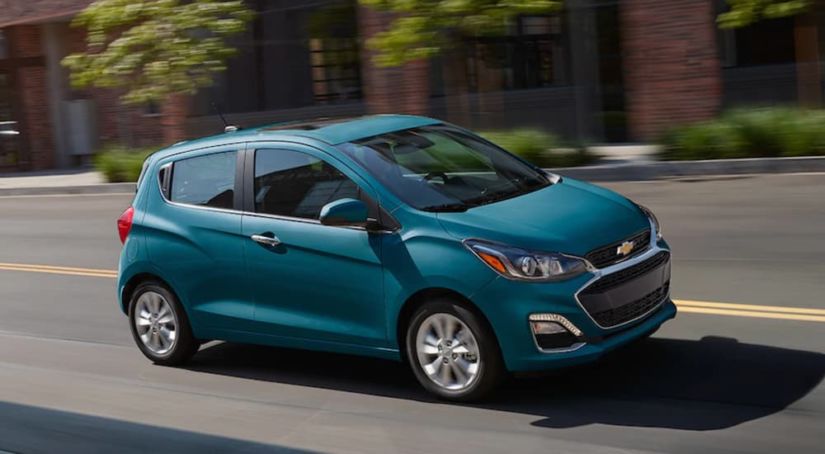 Teal 2019 Chevy Spark driving on city street