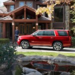 Man walking towards red 2019 Chevy Tahoe in front of mansion