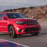 A red 2019 Jeep Trackhawk speeds through a turn on a race track
