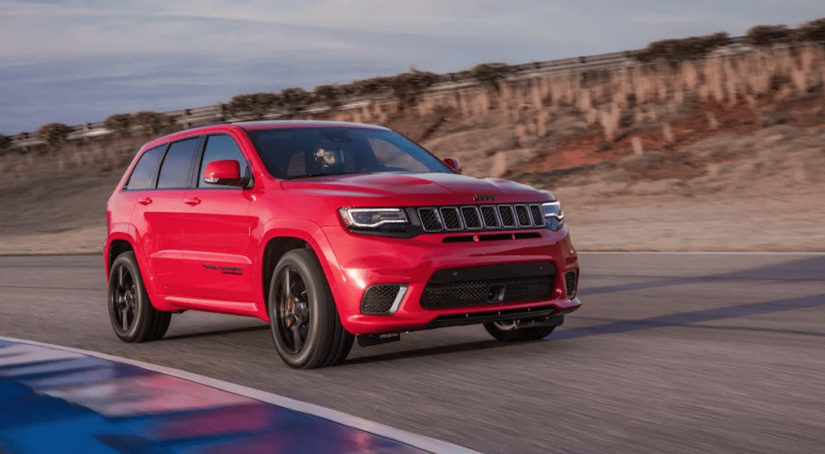 A red 2019 Jeep Trackhawk speeds through a turn on a race track