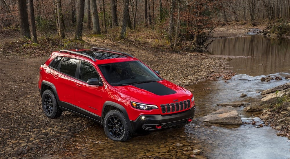 A red 2019 Jeep Cherokee navigates a river crossing