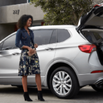 Man and woman loading a guitar into the back of a silver 2019 Buick Envision