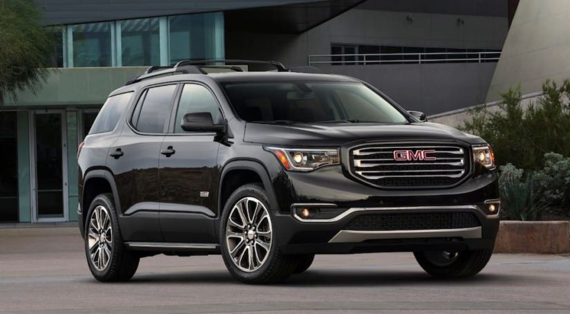 A black 2019 GMC Acadia All Terrain in front of a building