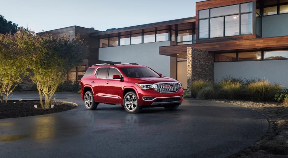 A red 2019 GMC Acadia Denali in front of a modern-looking mansion