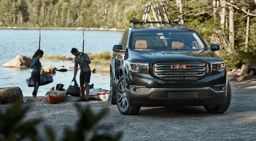 A man and woman prepare to kayak with a 2019 GMC Acadia All Terrain at the waterfront