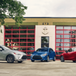 Silver, blue and red 2019 Toyota Yaris' in front of a glass building