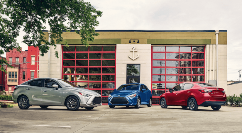Silver, blue and red 2019 Toyota Yaris' in front of a glass building