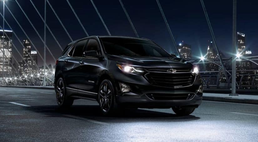 A black Midnight Edition 2020 Chevy Equinox, which wins when comparing the 2020 Chevy Equinox vs 2020 Toyota RAV4, is on a bridge at night.