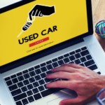 A man researches used cars for sale on a laptop