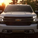 A white 2019 Chevy Silverado in front of a tree lined sunset