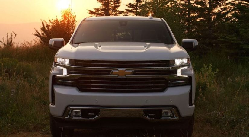 A white 2019 Chevy Silverado in front of a tree lined sunset