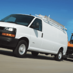 A white 2019 Chevrolet Express van tows a trailer