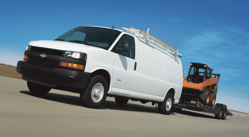 A white 2019 Chevrolet Express van tows a trailer
