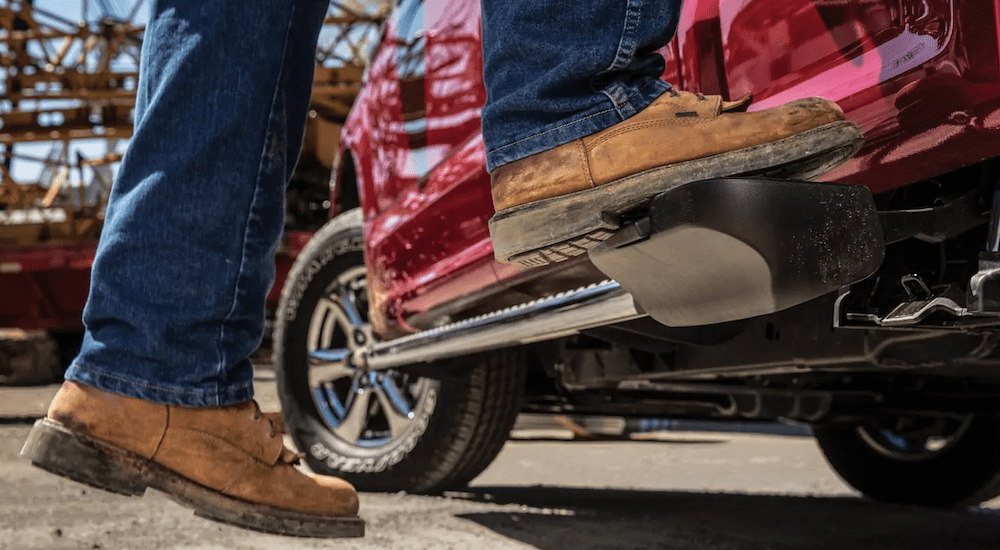 Stepping on the box side step of a red 2019 Ford F-150