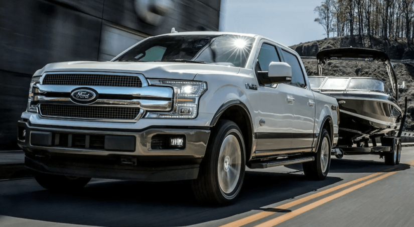 A white 2019 Ford F150 towing a boat and pulling away with the win of 2019 Ford F-150 vs 2019 Ram 1500