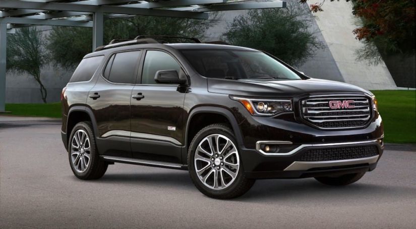 A black 2019 GMC Acadia All Terrain in front of an upscale home