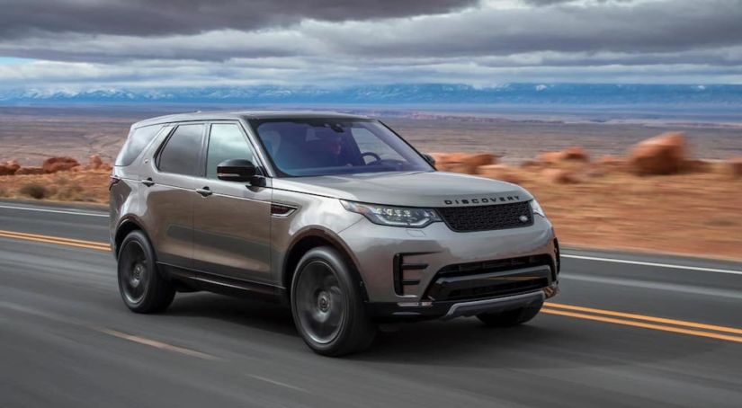 A silver 2019 Land Rover Discovery travels an empty desert highway